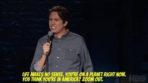 Gif of Pete Holmes on stage saying: Life makes no sense. You're on a planet right now. You think you're in America? Zoom out.
