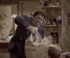 TV gif. George Wendt, as Norm on Cheers struggles to pull a raw turkey by the legs out of a brown grocery bag.
