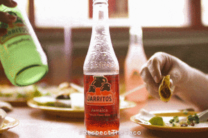 Ad gif. Half-full red Jarritos soda bottle positioned in between a hand setting down a green Jarritos soda bottle on the table while another hand picks up a half-eaten taco on the other side. Text in the bottom center reads, "Hashtag Respect The Taco."