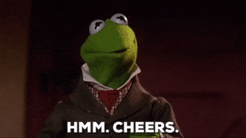 Muppets gif. Kermit, wearing a trench coat and a collared shirt, nods amiably and raises his cup. Text, "Hmm. Cheers."