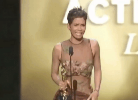 Celebrity gif. Halle Berry at the 2002 Academy Awards holds an award in one hand and sobs while blowing a kiss to someone in the crowd with the other hand.
