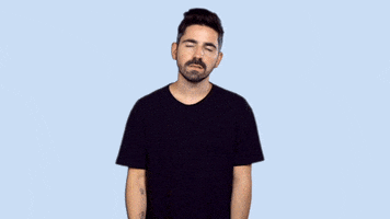 Video gif. A man in a black tee shirt facepalms and shakes his head in disappointed disbelief. 