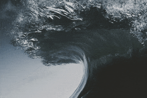 Digital art gif. An animated photo of an ocean wave perpetually curling against the sky.