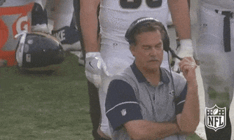 Sports gif. Jeff Fisher wears a Rams polo and headset as he looks down and rubs his forehead in defeat.