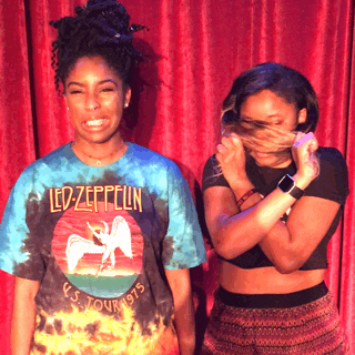 Celebrity gif. 2 Dope Queens' Jessica Williams cringing next to Phoebe Robinson, who pulls her hair to cover her face, as they stand in front of a red curtain.