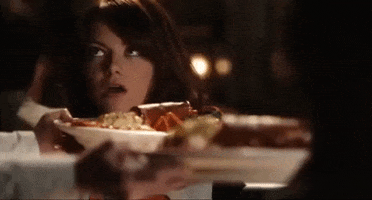 Movie gif. Emma Stone as Olive Penderghast in Easy A, breathes in a plate of food, saying "yuuuuuuuuuuuuuuum," rolling her eyes back into her head in dramatic overwhelm, and looking to her companion to provoke a reaction.