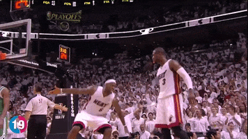 Sports gif. Lebron James and Dwayne Wade in the Miami Heat share a big high five, with Lebron swinging his arm wide.