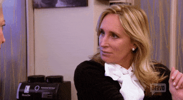 Reality TV gif. Sonja Morgan from Real Housewives of New York looks and two people back and forth in confusion, putting a hand up as she tries to figure out what the point is.