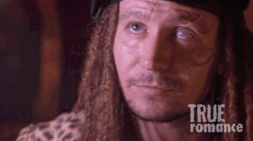 Movie gif. Gary Oldman as Drexl Spivey in True Romance looks up and tilts his head to the side, grinning lustfully.