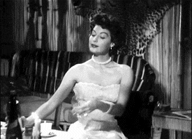 Celebrity gif. Ava Gardner with style and grace cheerfully pours herself a glass of wine. 