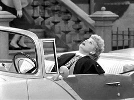 TV gif. Lucille Ball in I Love Lucy behind the wheel of a convertible, leaning back dramatically, exhausted.