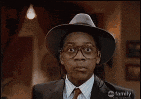 TV gif. We zoom in on Jaleel White as Steve Urkel from Family Matters, who is wearing a suit with a fedora. He tilts his head around to give us several wacky, suspicious looks...then ends up looking scared.