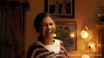 Movie gif. Zendaya as MJ in Spiderman No Way Home Behind the scenes looks at us while pumping her fists in the air. She has a big smile on her face and scrunched her nose. 