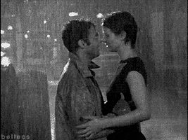 TV gif. Black and white scene of Cynthia Nixon as Miranda and David Eigenberg as Steve in Sex and the City passionately making out in the pouring rain.
