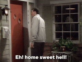 TV gif. Ed O'Neill as Al on Married with Children stands at the front door of a home and says, "eh! home sweet hell!" which appears as text.
