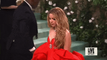 Met Gala 2024 gif. Shakira wearing a red Carolina Herrera gown, tosses her hair in slomo.