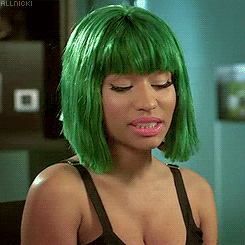 Celebrity gif. Nicki Minaj wears a green bob wig and has her eyes closed as she smiles and shrugs her shoulders.