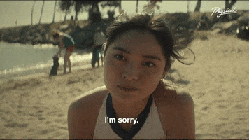 TV gif. Ashley Liao as Simone in Physical leans toward us as a beach breeze ruffles her hair and she says, "I'm sorry." 