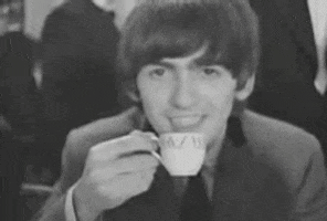 Celebrity gif. A young George Harrison raises his eyebrows as he sips tea from a tiny cup.