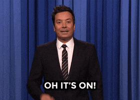 Tonight Show gif. Jimmy Fallon as host mimes taking off a pair of earrings as he says, "Oh it's on," text which also appears on screen. He's ready to throw down.