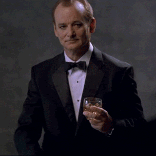 Celebrity gif. Bill Murray holds a glass of alcohol in his hand and points at us while lifting his eyebrow up. 