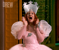 TV gif. Drew Barrymore dressed as Glinda the Good Witch from The Wizard of Oz drops her jaw and throws her hands to her face in dramatic surprise.
