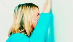 Video gif. Woman slams her hands and face against a white wall as she screams and cries in pain.