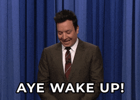The Tonight Show gif. Jimmy Fallon pretends his hand is a smart phone and frustratingly pokes it as he says, “Aye Wake up!”