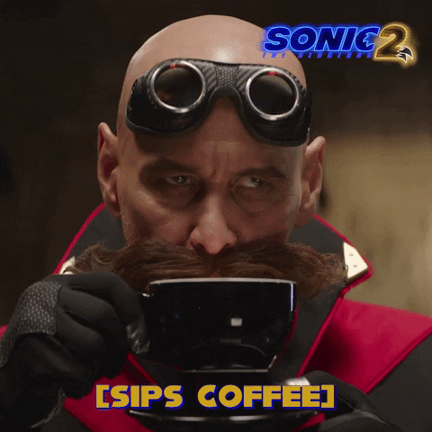 Movie. Jim Carrey as Dr. Robotnik in Sonic the Hedgehog 2 sips coffee and smacks his lips, testing the taste. Text, “sips coffee.”