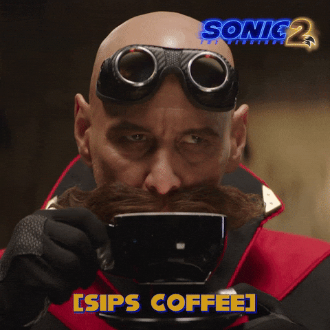 Movie. Jim Carrey as Dr. Robotnik in Sonic the Hedgehog 2 sips coffee and smacks his lips, testing the taste. Text, “sips coffee.”