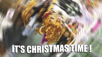Video gif. Decorated with shiny gold Christmas garlands, three young women strut through a superstore carrying more garlands, a giant plastic candy cane, a giant gold snowflake, and other festive items. The woman in the middle takes off a Santa hat and tosses it at us playfully. Wavy text, "It's Christmas time!"
