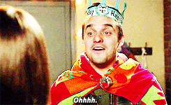 TV gif. Jake Johnson as Nick Miller on New Girl wears a paper crown and a towel as a cape looks at someone with a smile and says, “Ohhhh.”