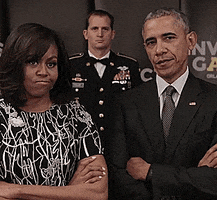 Political gif. Barack and Michelle Obama have a power duo stance as they stare straight at us with their arms crossed. Behind them, a government official drops an invisible mic and mouths, "Boom."