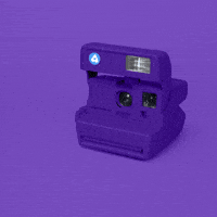 Video gif. A purple polaroid camera prints out a picture that has the word, "YAS," on it and the flash goes off.