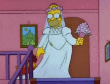 The Simpsons gif. Dressed in a white wedding dress, Homer takes a step down the stairs and pauses to smell his bouquet.