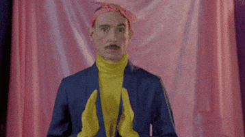 Celebrity gif. Genís Segarra of Hidrogenesse, a Catalan pop band, wears a yellow turtleneck, blue suit jacket, and matching yellow gloves. He slowly moves his hands away from each other like he's measuring the length of something.