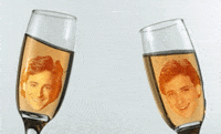 Digital art gif. Bob Saget as Danny from Full House. Danny's face is edited to be floating inside two champagne flutes and they cheers together while his face grins happily.