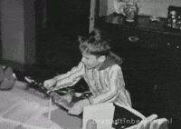 Video gif. Black and white home-movie style video of a young boy wearing a long night shirt looking at us while jumping and clapping with excitement. Text, "Yay."