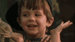 Movie gif. A young boy wearing a cocked baseball cap brings his hands under his chin and curls them up in delight, smiling the whole way.