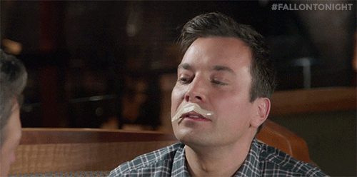 The Tonight Show gif. Jimmy Fallon tilts his head back and has a slice of sashimi on his lip like a white mustache. He reaches his tongue up and lets the fish go in his mouth. He then smirks and winks at the person across from him.
