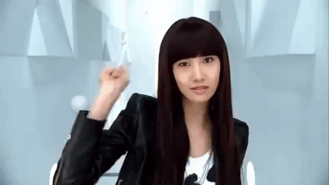 Music video gif. In Run Devil Run, Yoona from Girls Generation makes a firework gesture at us with her hand, as she stands in a black leather jacket against a spotless white background with bright, flickering lights.