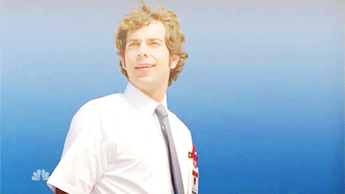 TV gif. Zachary Levi as Chuck Bartowski in Chuck stands in a white collared shirt and blue tie underneath a heavenly glow. A smile of awe spreads across his face as he slowly raises his hand to wave.