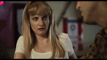 Movie gif. Melissa Rauch as Hope in The Bronze stares with dismay at Thomas Middleditch as Ben while he speaks.