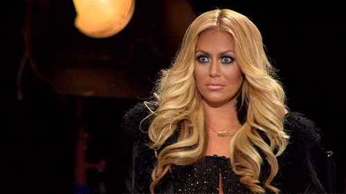 Celebrity gif. Aubrey O'Day gives a wide-eyed straight face and her mouth stretches into a sneer.