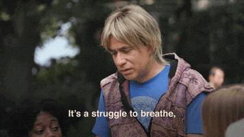 TV gif. Fred Scharmen as a hippie on Portlandia with a group of people at a park, saying, "It's a struggle to breathe, that's how hungry I am."