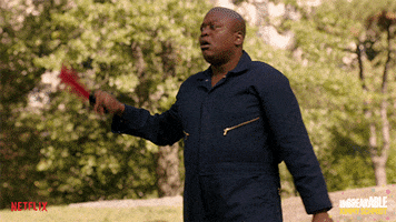 TV gif. Actor Tituss Burgess of The Unbreakable Kimmy Schmidt wears a blue workman's jumpsuit and fans himself with a beautiful red folding fan.
