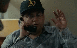 Movie gif. Jonah Hill as Peter Brand in Moneyball is on the phone and pauses, waiting for something. He then slowly forms his hand into a fist and grits his teeth in excitement. 