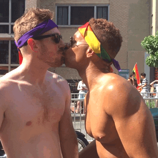 Video gif. Two shirtless men in sunglasses and bandannas share a smooch.