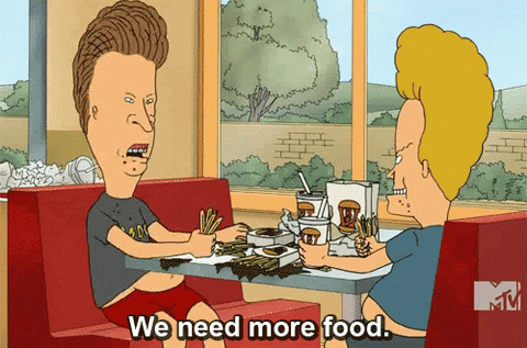 Cartoon gif. Beavis and Butt-head sit in a messy restaurant booth holding fistfuls of fries as Butt-head says, "We need more food."
