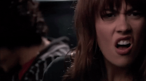 Video gif. A woman cringes at something in disgust and turns her head to look away. 